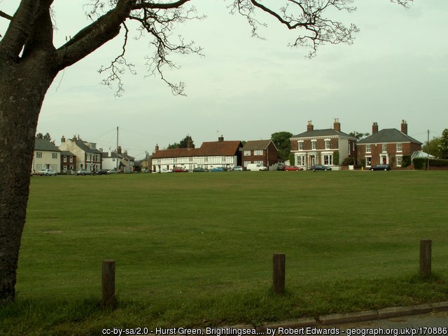 A large green with houses on the far side.