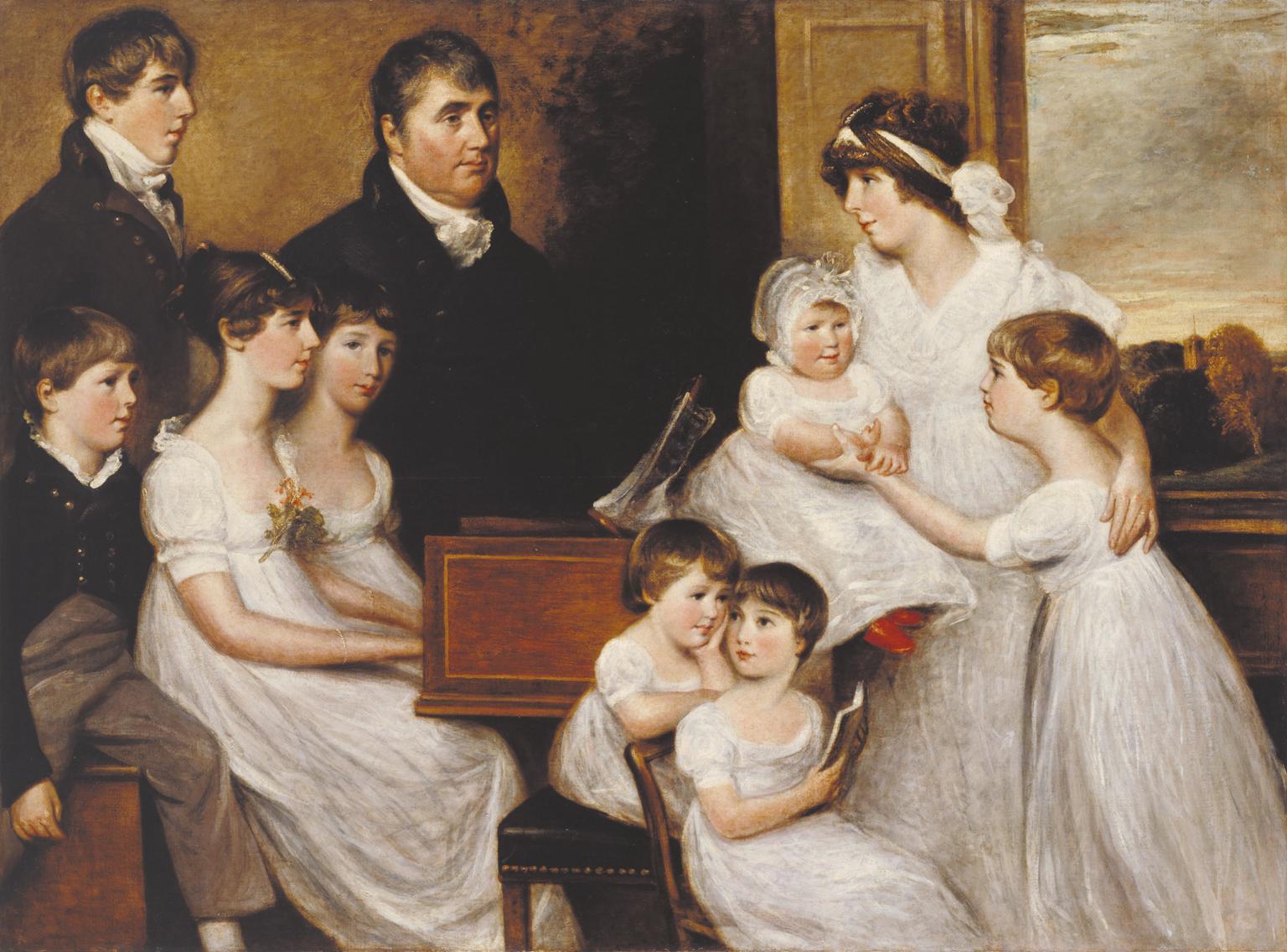 A family of eight stand around a piano. Through the window behind them, a church tower can just about be seen.