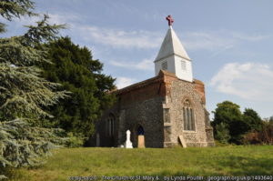 The unusual-looking church with squat wooden tower on top of the flint body of the church.